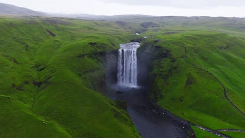 Der Skogafoss-Wasserfall fließt durch grüne Klippen in Island