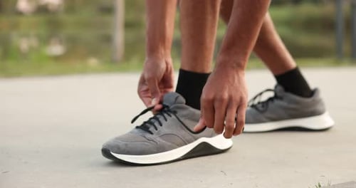 Runner tying shoelace of his sneaker outdoors, closeup