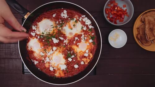 Garnishing shakshouka with coriander. Top view.