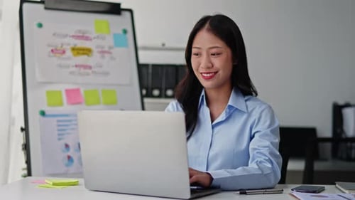 Geschäftsfrau arbeitet in Büroräumen am Laptop.