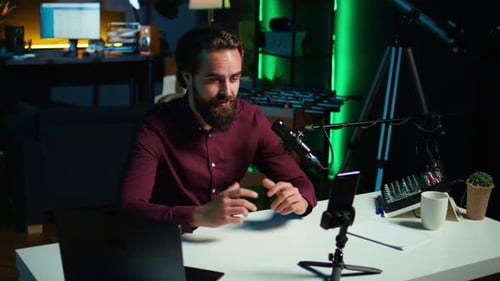 Man Recording Video at Desk in Dark Room