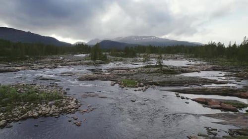 Drone Gliding Left Along River With Lush Pine Trees And Mountain Vista