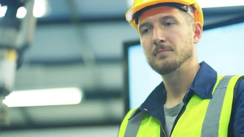 Close up face of Caucasian technican or engineer worker look robotic arm working in factory