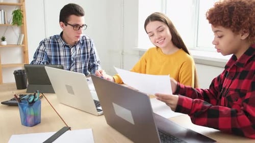 Young Adults Working Together at Desks with Laptops