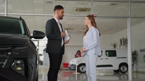 Car Salesman with Client Shaking Hands in Showroom