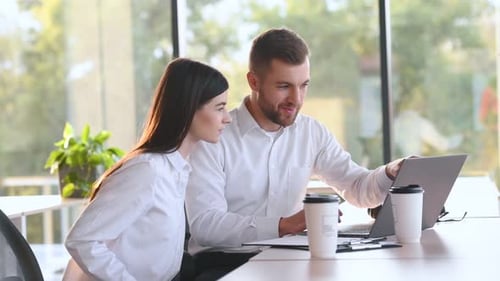 Sorrindo e dando um “high five”. Homem e mulher estão trabalhando juntos no escritório moderno