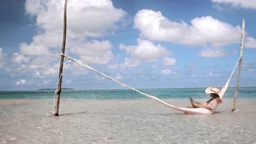 Of Woman Working on Laptop Computer on Hammock in Blue Ocean