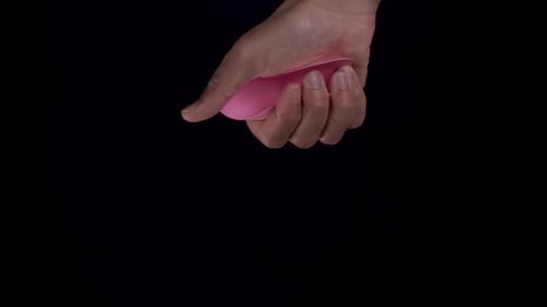 Hand Squeezes Pink Heart, Crumples on Black