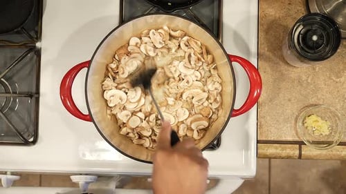 Sauteing organic sliced mushrooms in a pot over the stove for a vegan recipe - overhead view WILD RI
