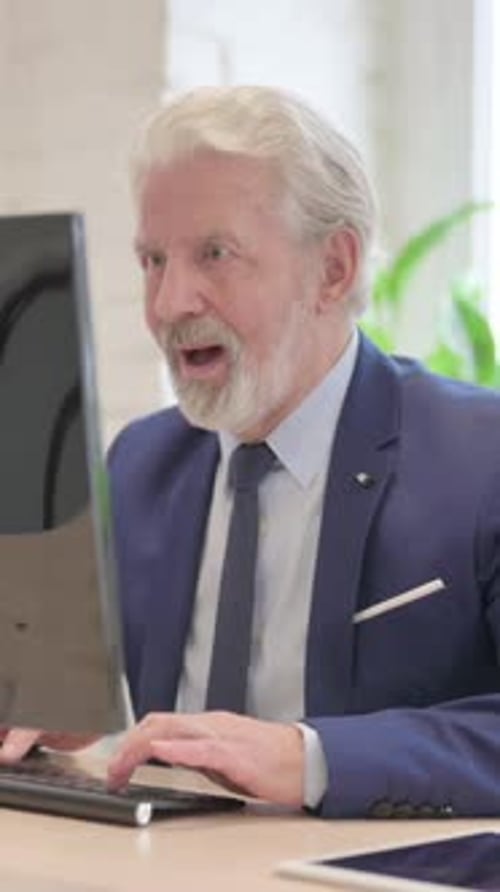 Senior Man Celebrates Success at Office Computer
