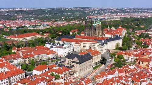 A breathtaking view of Prague showcases the iconic castle, red rooftops, and lush green hills under