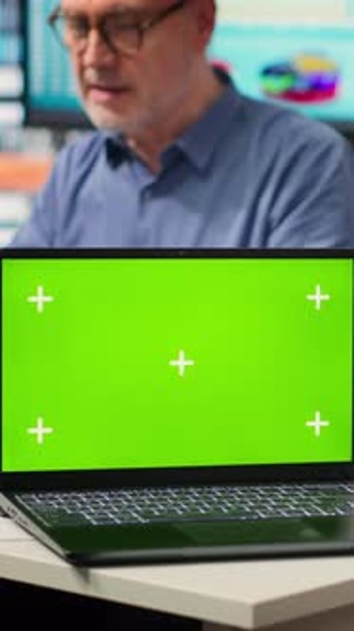 Man Working on Laptop with Green Screen in Office