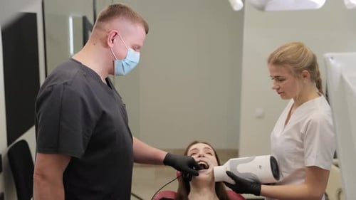 A Professional Dentist and His Assistant Perform a Complex Procedure in a Modern Clinic with