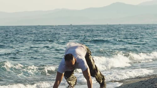 Muscular Man Runs and Exercises on Wet Beach