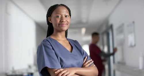 Portrait of happy african american female doctor wearing scrubs in hospital, slow motion