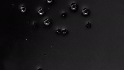 Animated Metallic Bullet Holes Appearing on Dark Surface