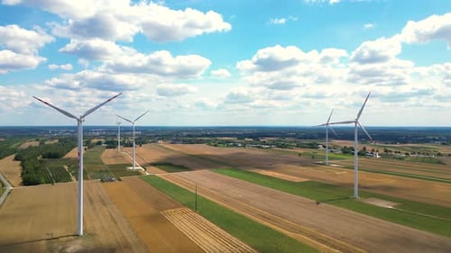 Wind turbines generate clean energy in expansive landscapes under a bright blue sky during the after