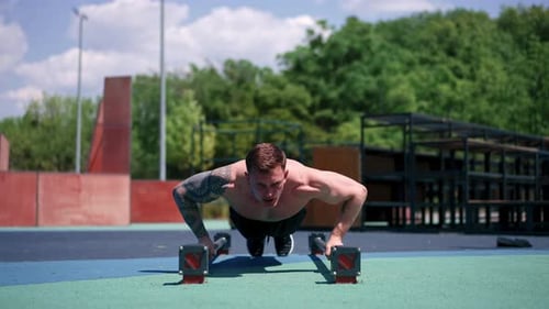 young pumped-up athlete doing push-ups from the ground during street training endurance exercise
