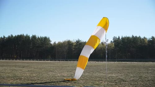 Windsack an der Stange flattert schwach im Wind in der Nähe der Landebahn des Flughafens