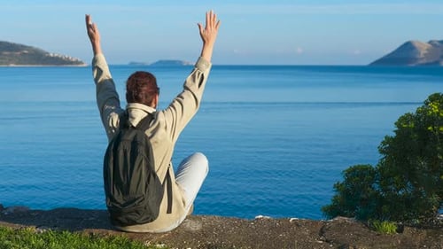 Traveler Raising Arms By the Sea Embracing Freedom and Serenity