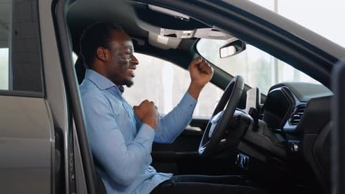 Man Celebrating New Car Purchase in Showroom