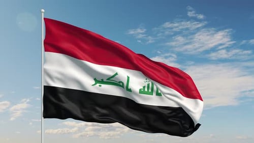 La bandera nacional de Irak ondea con fuerza contra un cielo brillante y despejado