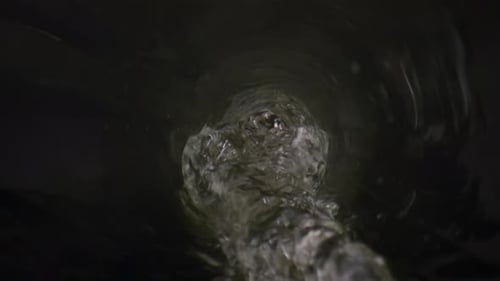 Clear mineral water flowing from glass bottle in super slow motion
