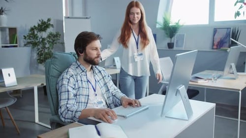 A Man Works at His Desk with a Woman Behind Him Showing Support