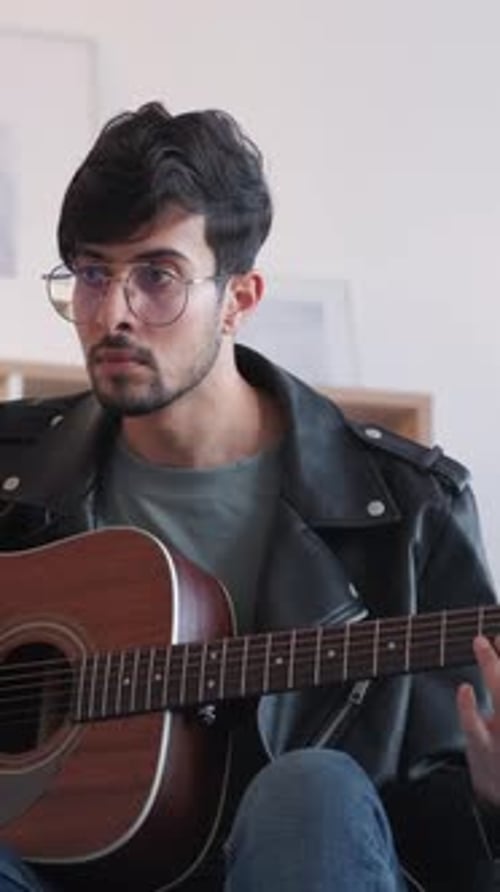 Young Man Plays Acoustic Guitar in Home Setting