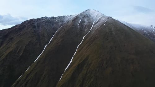 Cinematic drone shot of the Caucasus mountains in Georgia with two small snow-covered valleys