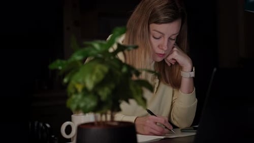 Mulher trabalhando em casa no local de trabalho à noite usando laptop