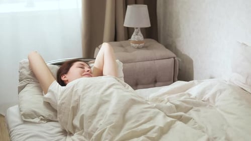 Woman Stretching in Bed After Waking Up