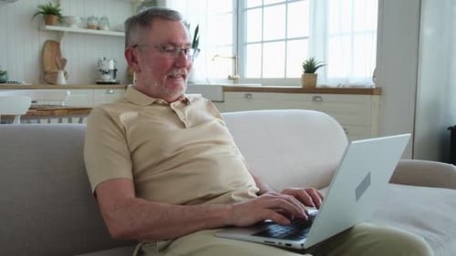 Senior Man Using Laptop at Home on Couch
