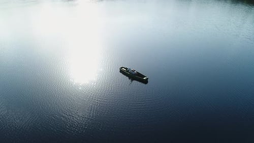 A Man Plays the Guitar While Lying in a Wooden Boat Aerial View