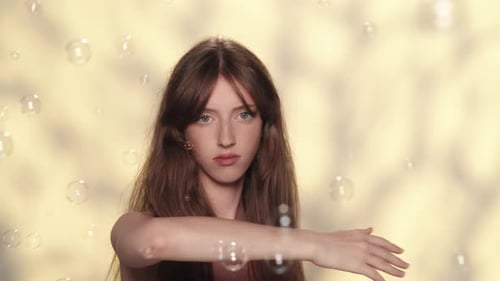Appealing Brunette Girl Looking Annoyed By Many Soap Bubbles Flying Around Her