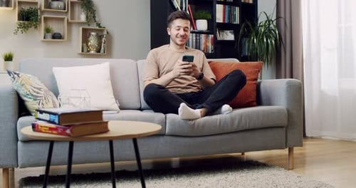 Man Relaxing on Sofa Using Mobile Phone Indoors