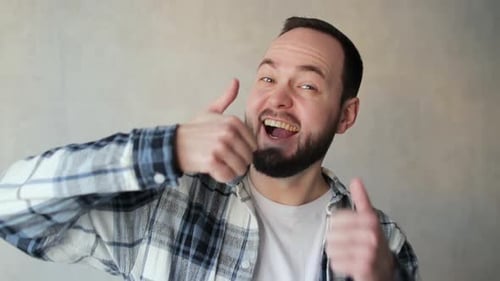 Glücklicher Mann schaut zustimmend in die Kamera und zeigt die Daumen nach oben als positives Zeichen Gute Nachricht