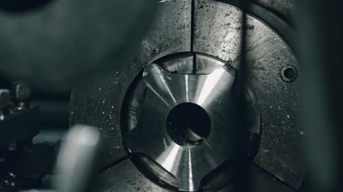 Metalwork lathe chuck adjustment by skilled machinist in industrial setting