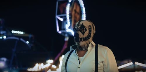 Man with scary mask at amusement park at night