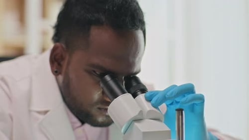 Scientist Concentrates on Microscope Research in Laboratory Setting