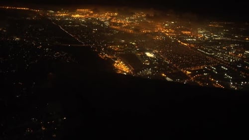 Night time shot of a glowing city from an airplane.
