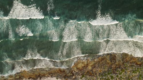 Tidal Ocean Waves Crash Onto Rocky Coastal Reef From Aerial Top View