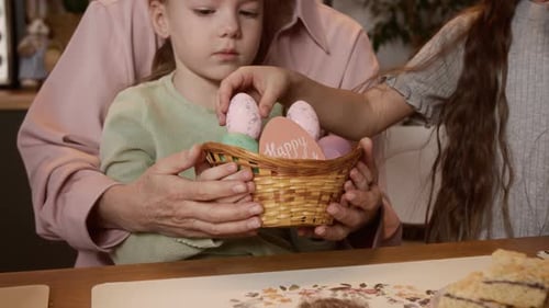 Kleines Mädchen und ihre Großmutter füllen Osterkorb mit bunten Eiern
