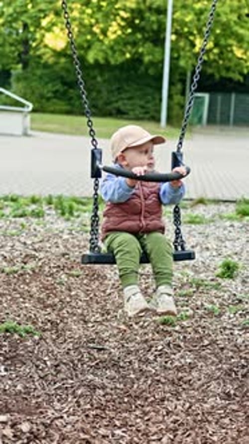 Cute Infant Sitting on a Swing at the Park
