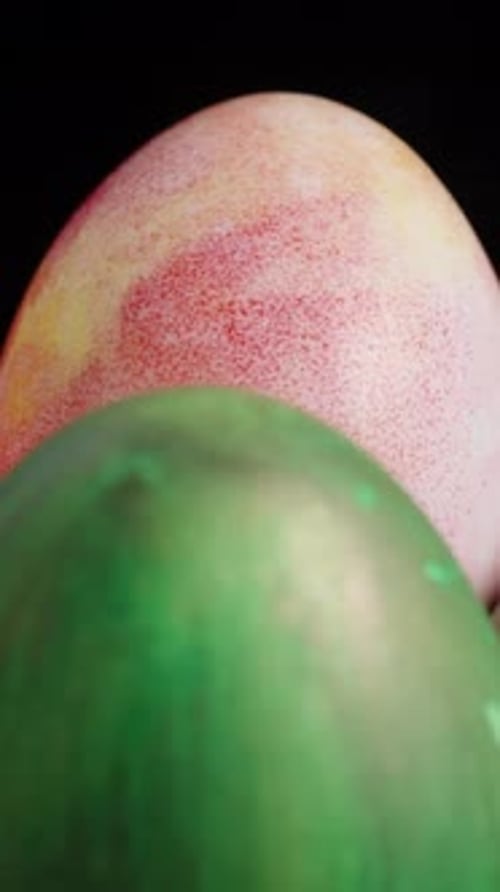 Vertical video. A group of colorful Easter eggs, including green, orange, and marbled pink-yellow,