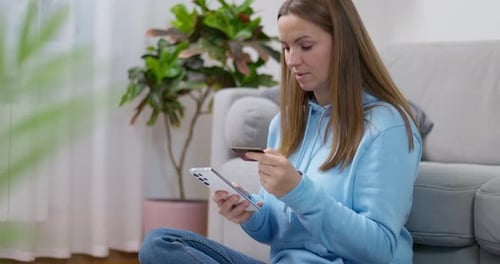 Woman Comparing Credit Card and Smartphone
