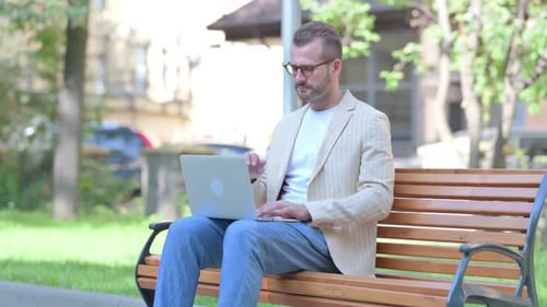 Man Works on Laptop in Urban Park Setting