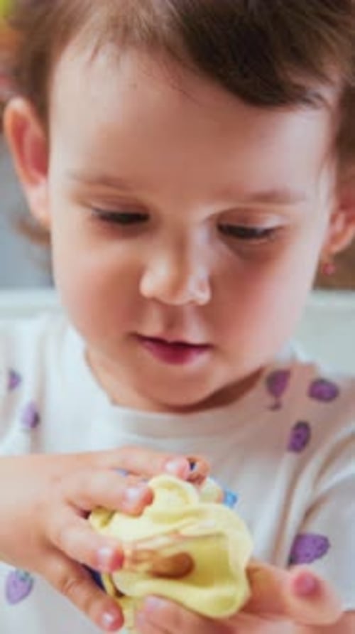 Kleines Kind inspiziert winziges Spielzeugkind untersucht kleines Spielzeug und streckt Schleim friedlich