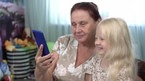 Grandmother and Child Using a Smartphone Indoors