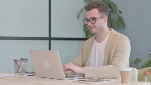 Man At Desk Making Video Call On Laptop